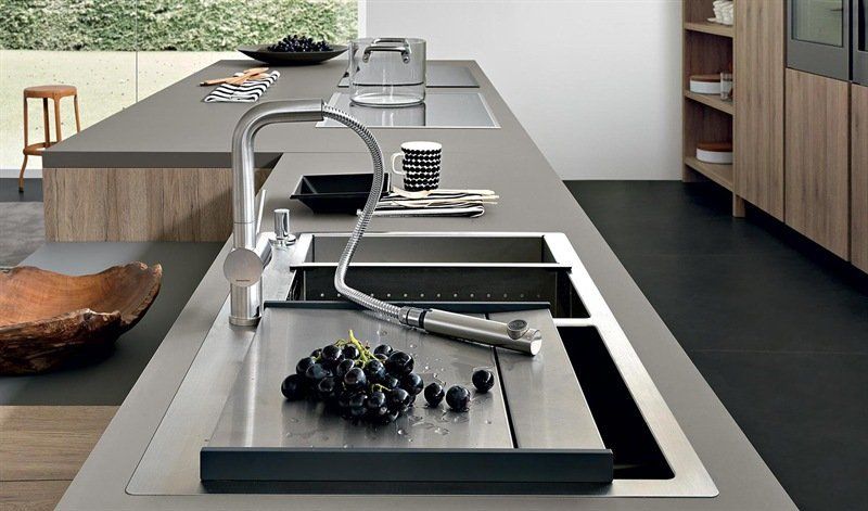 Una cucina con due lavandini e una ciotola di uva sul bancone