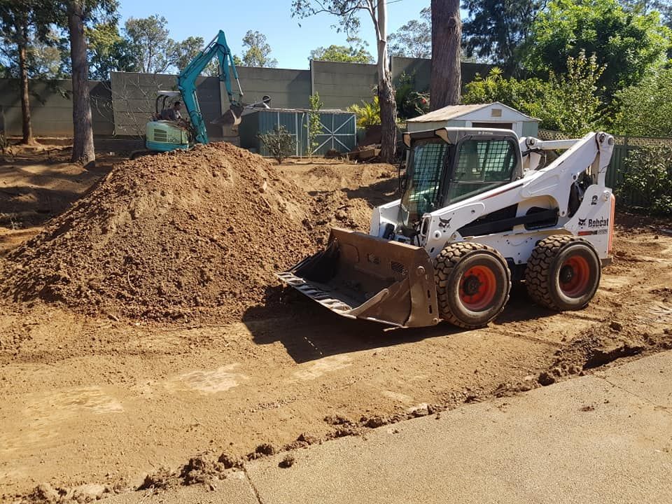 A bobcat loader is moving dirt on a construction site