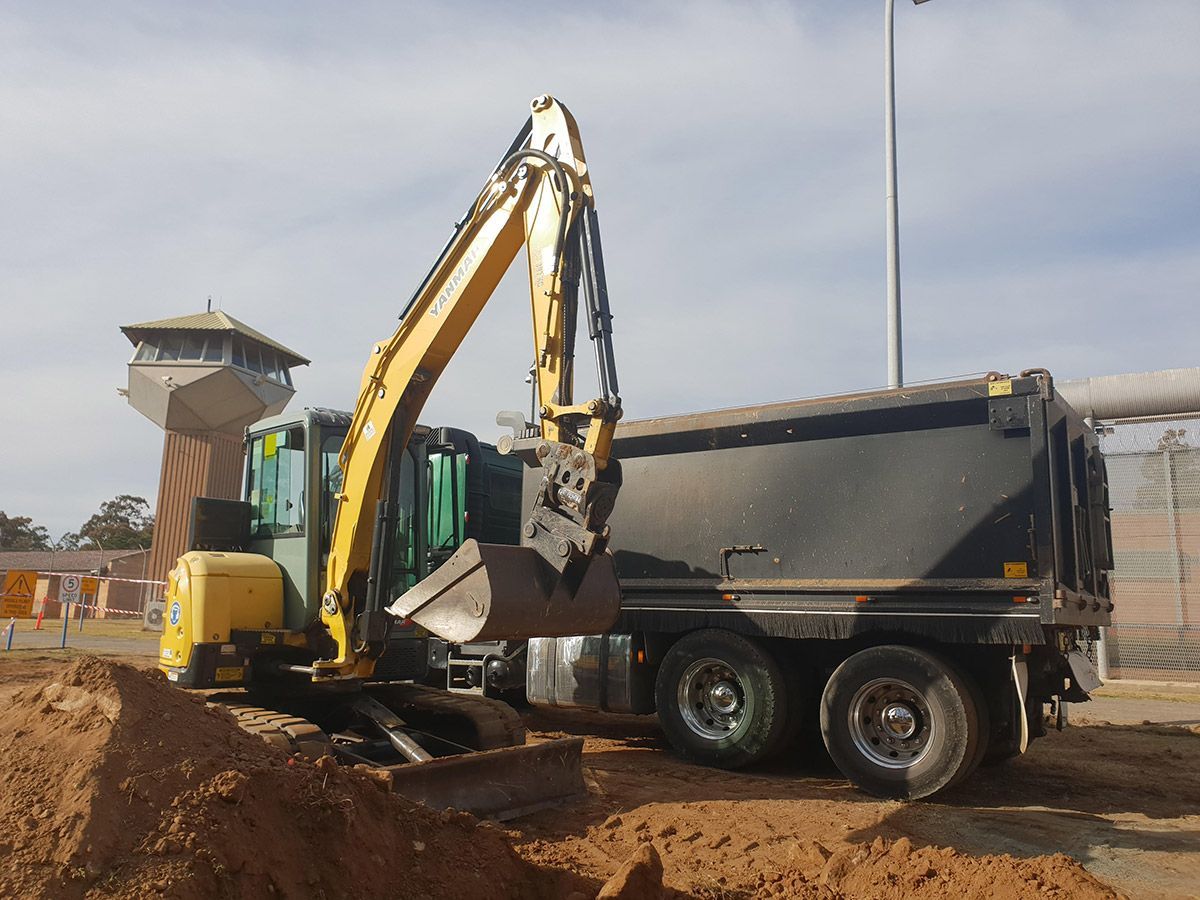 A yellow excavator is loading dirt into a dump truck