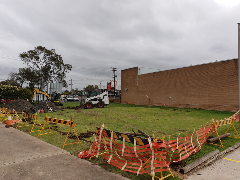 A construction site with a bulldozer and a brick building in the background.