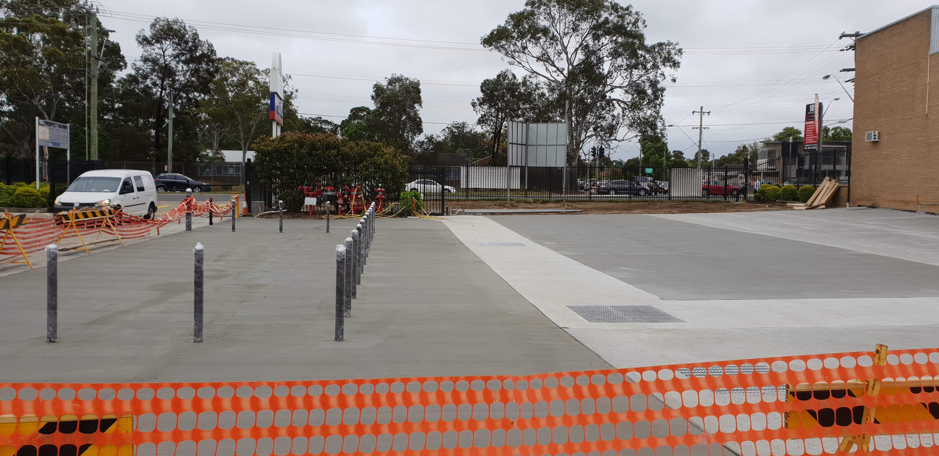 A parking lot with a fence around it and a white van in the background.