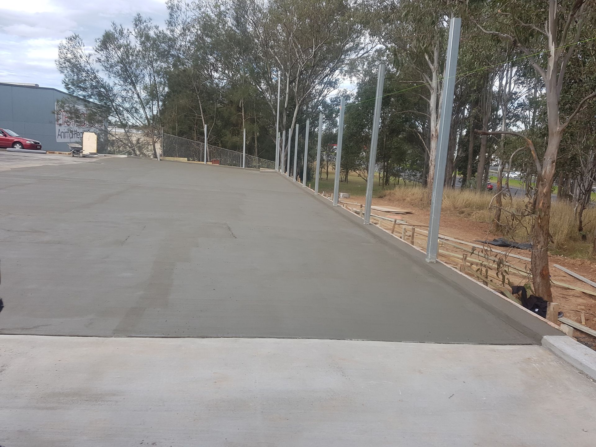 A concrete driveway with a fence and trees in the background.