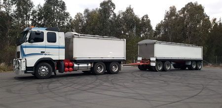 A white truck with a trailer attached to it is parked in a parking lot.