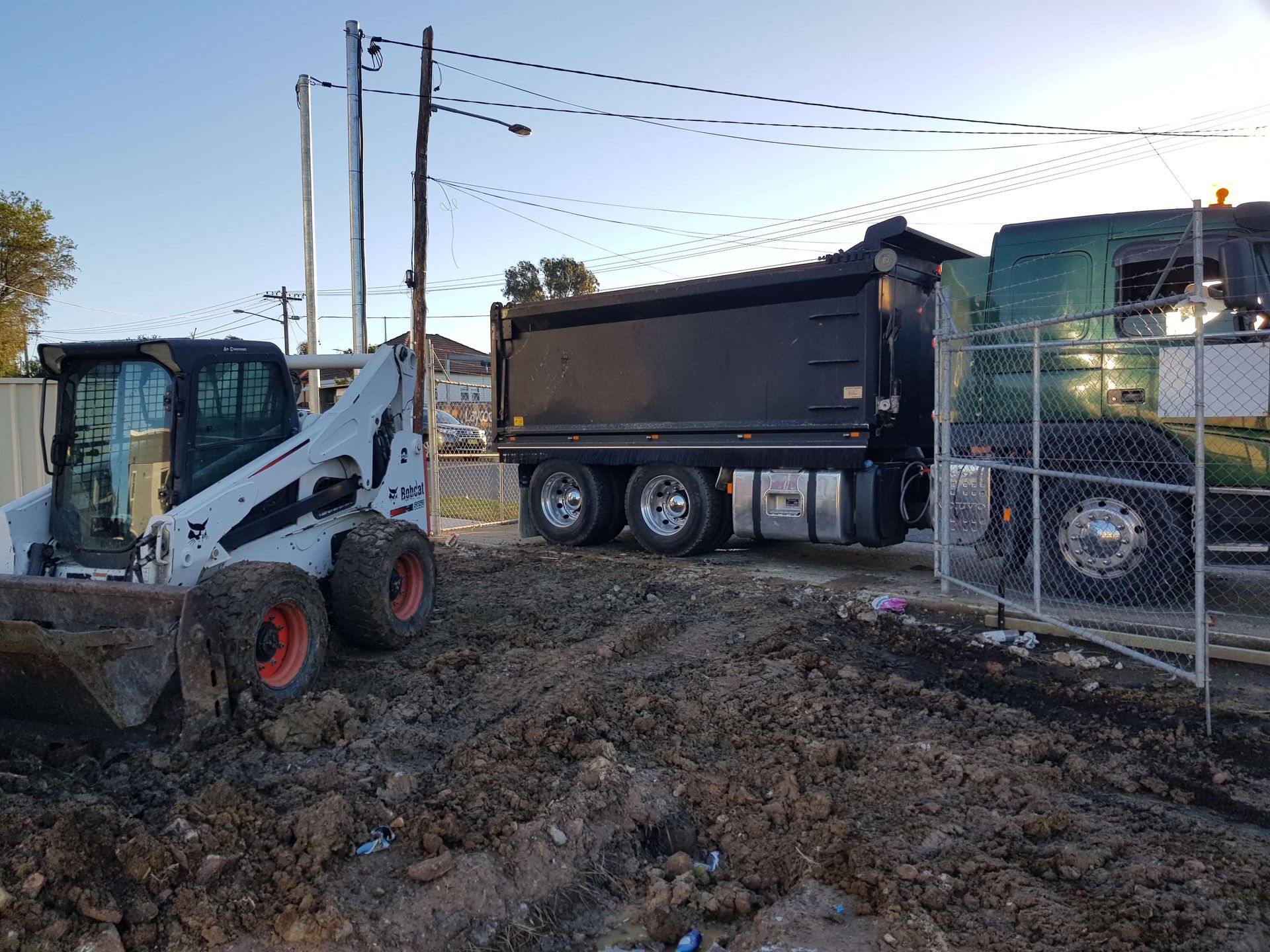 A dump truck is parked next to a bulldozer on a dirt road.