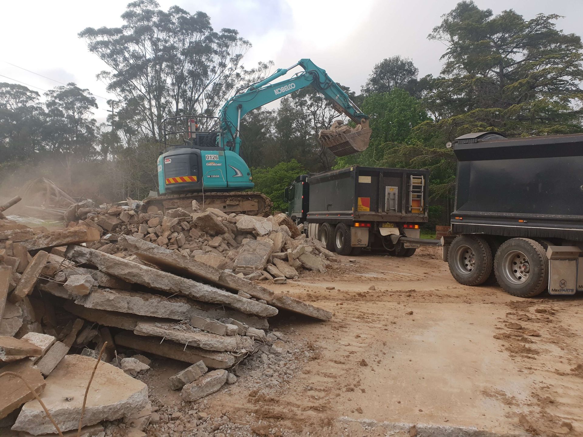 A dump truck is being loaded with rocks by an excavator.