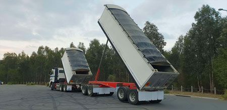 Two dump trucks are parked next to each other in a parking lot.