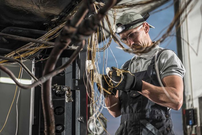 A man is working on a bunch of wires in a garage.