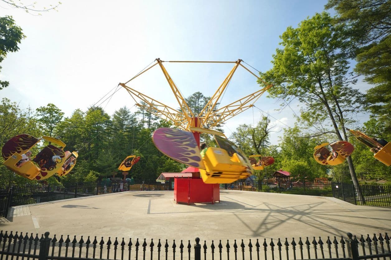 Amusement park ride with yellow and red chairs, spinning in the air.