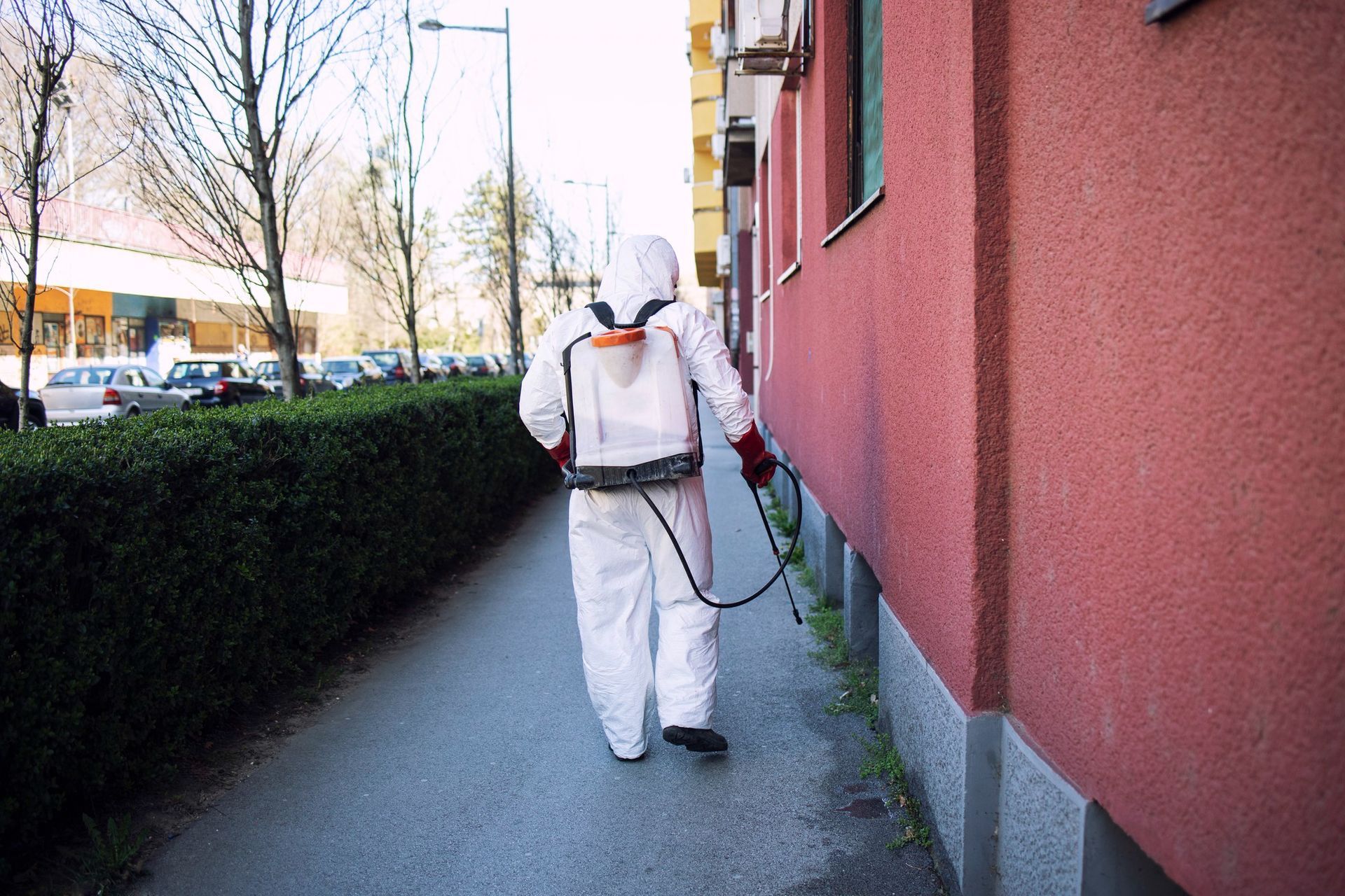 A man in a protective suit is spraying a building with a sprayer