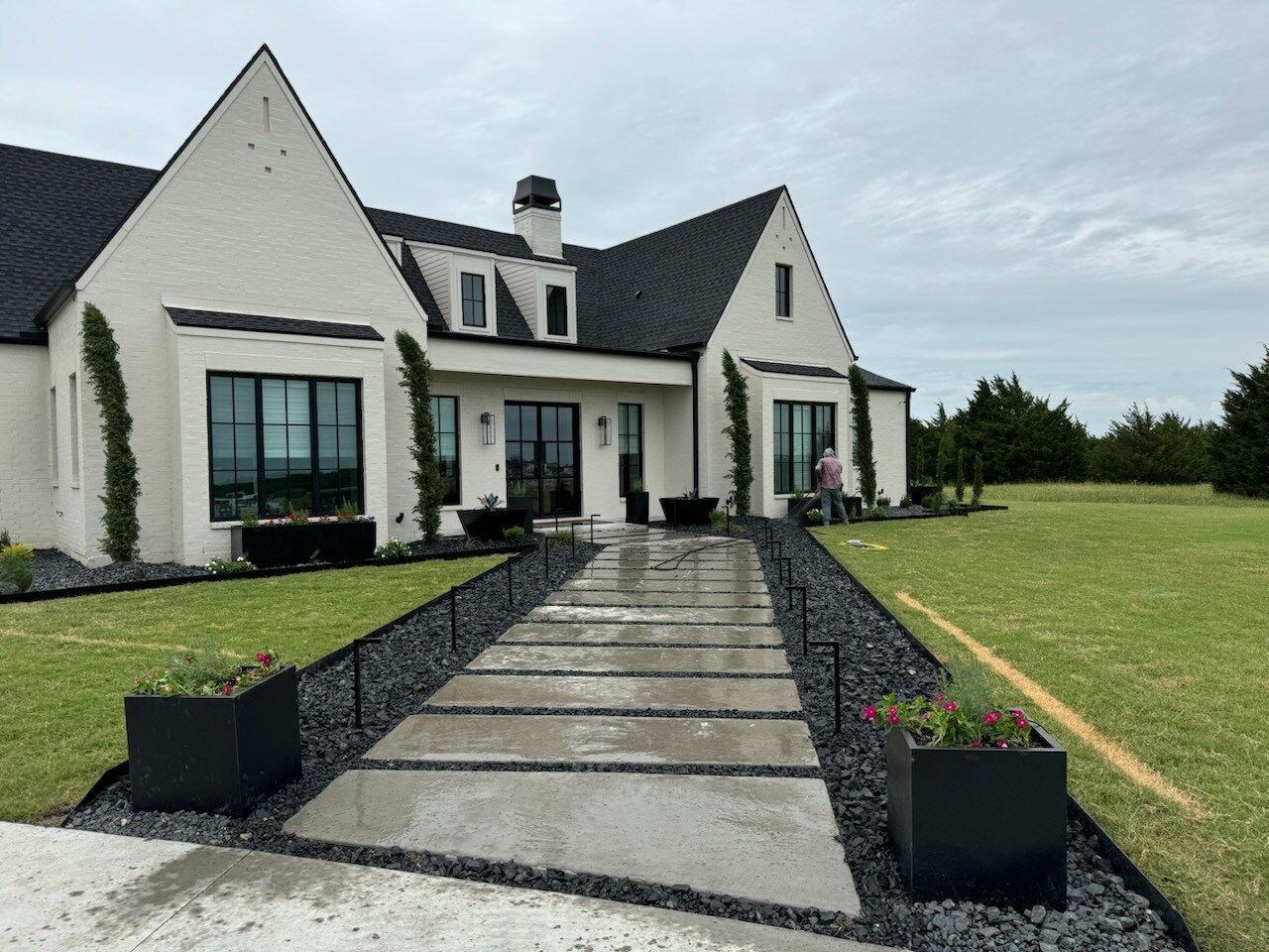 The backyard of a brick house with a fence and a lot of grass.