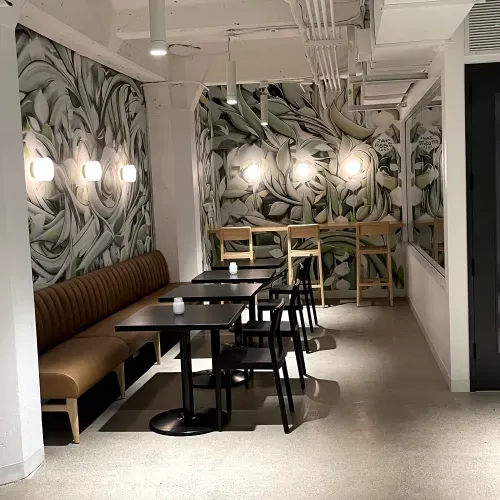 A restaurant with tables and chairs and a mural on the wall