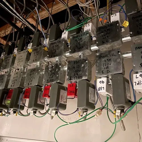 A bunch of electrical boxes are lined up on a wall