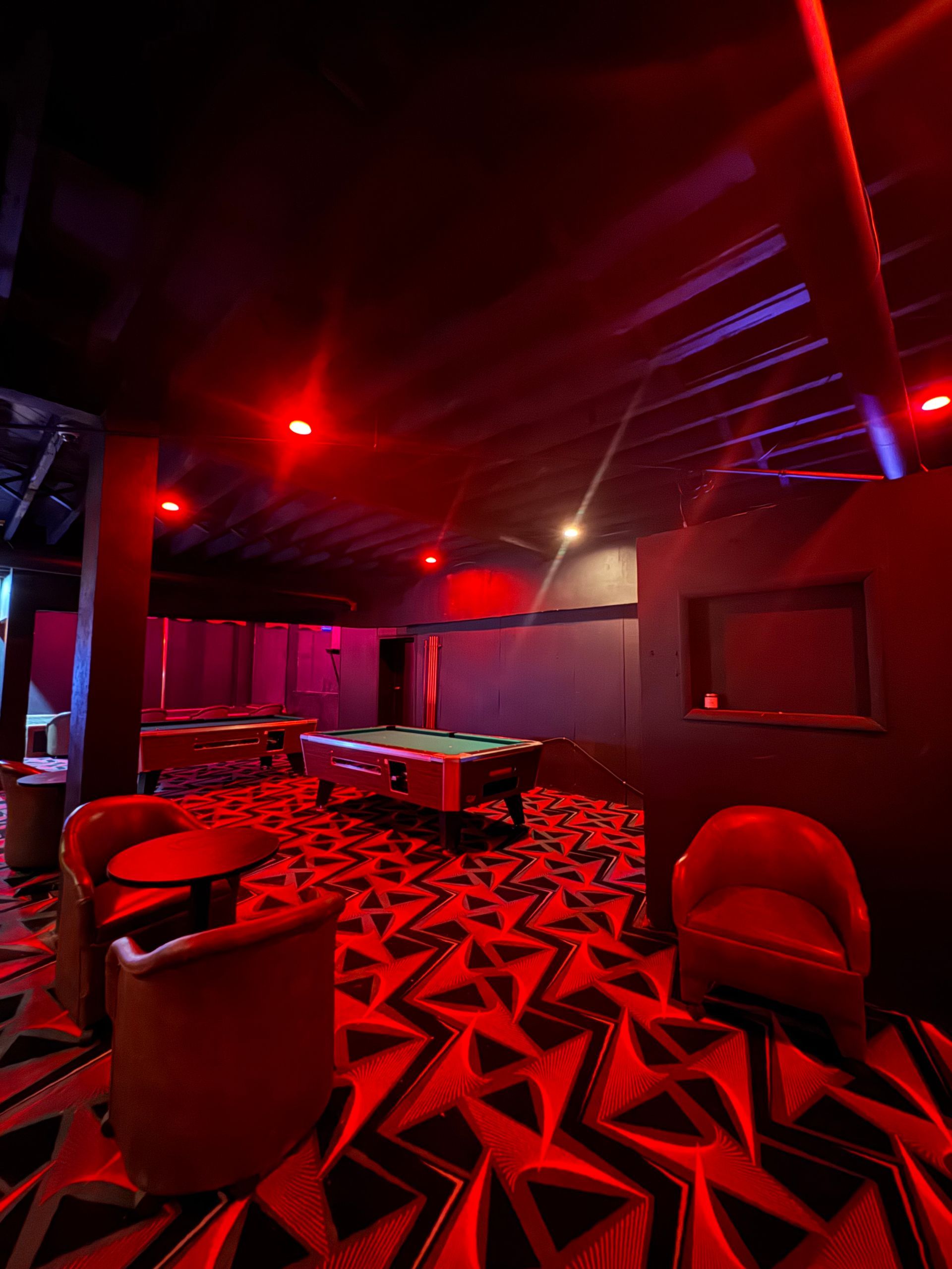 A pool table in a dark room with red lights