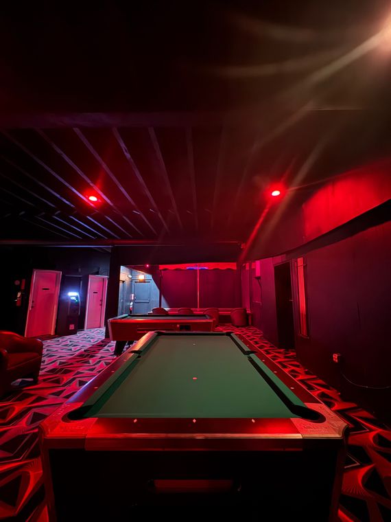 A pool table in a dark room with red lights