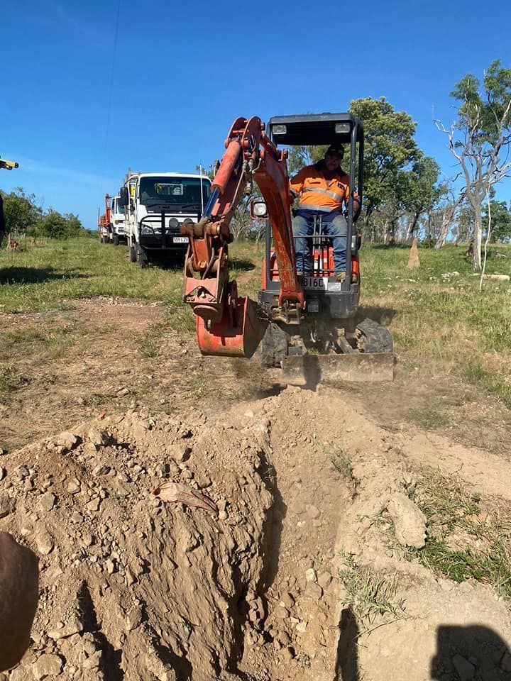 Man Driving A Small Excavator In A Dirt Field — FNQ Drilling in Cairns, QLD