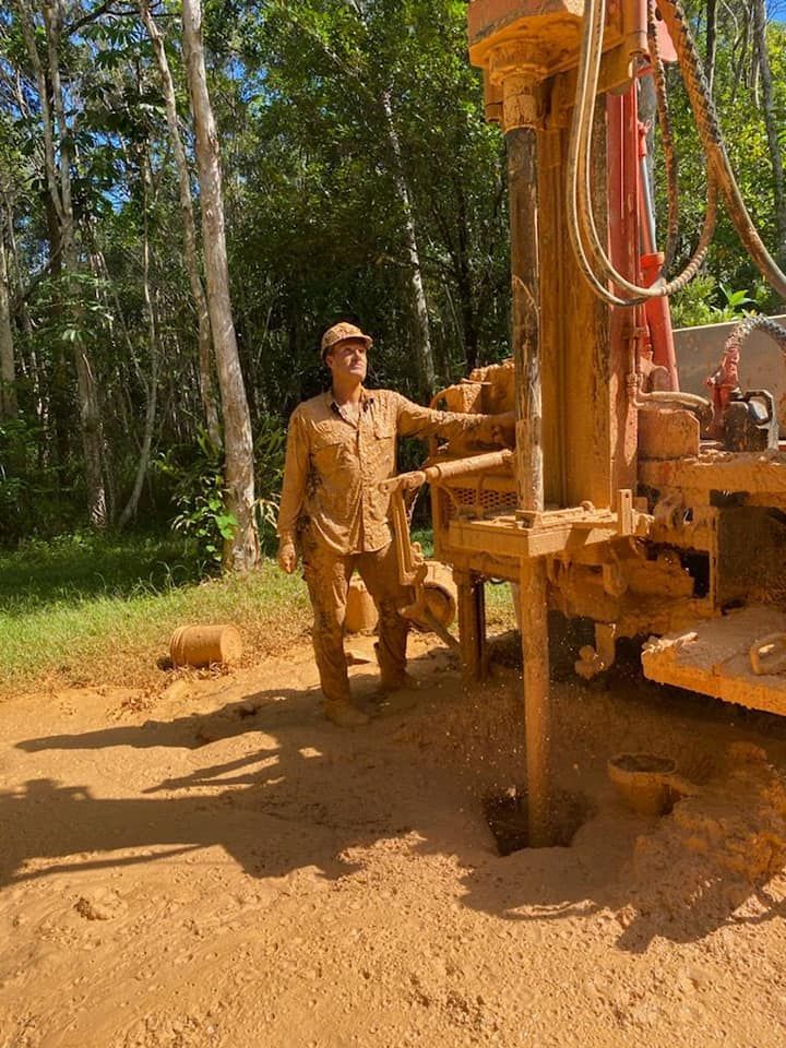 Man Is Standing Next To A Machine In The Dirt — FNQ Drilling in Georgetown, QLD