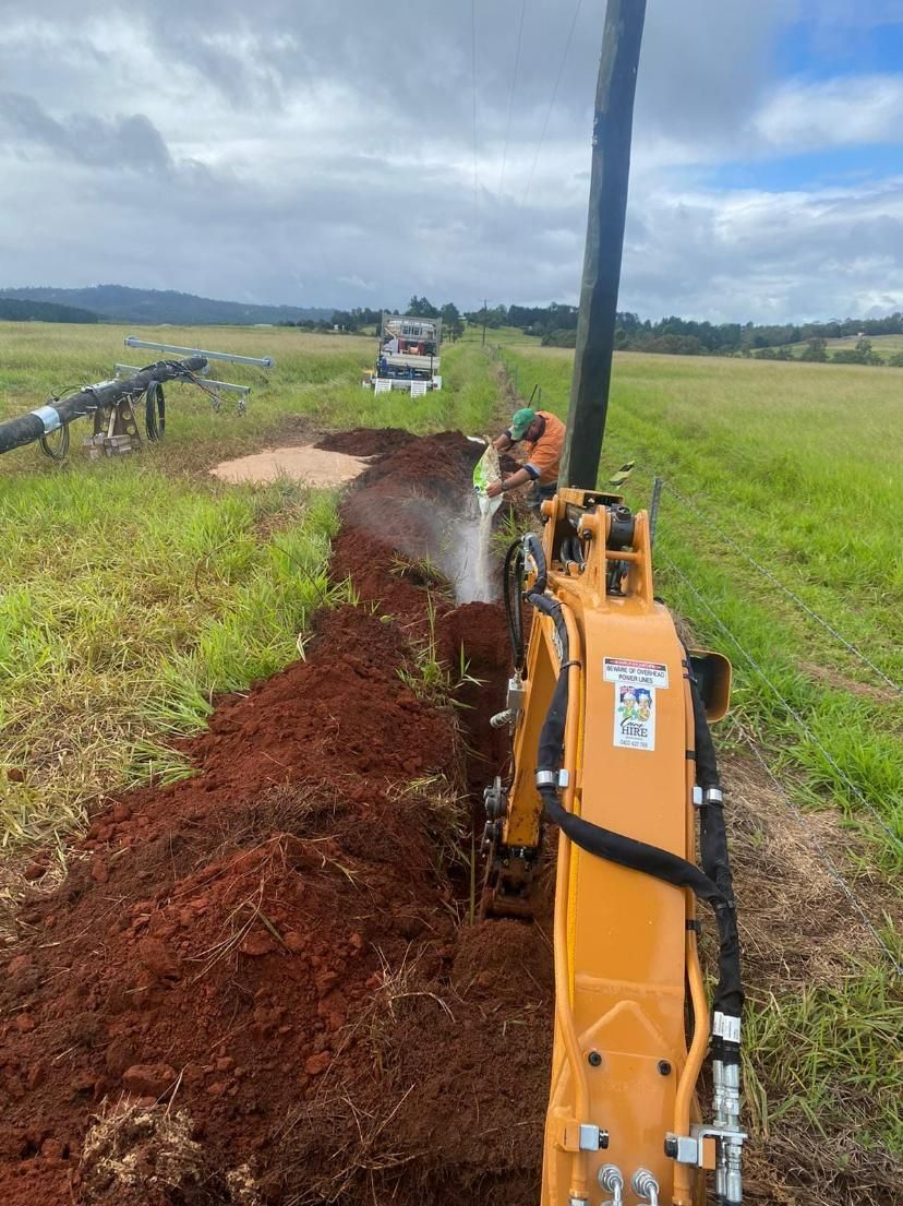 Yellow Excavator Is Digging A Hole In A Field — FNQ Drilling in Bamboo, QLD