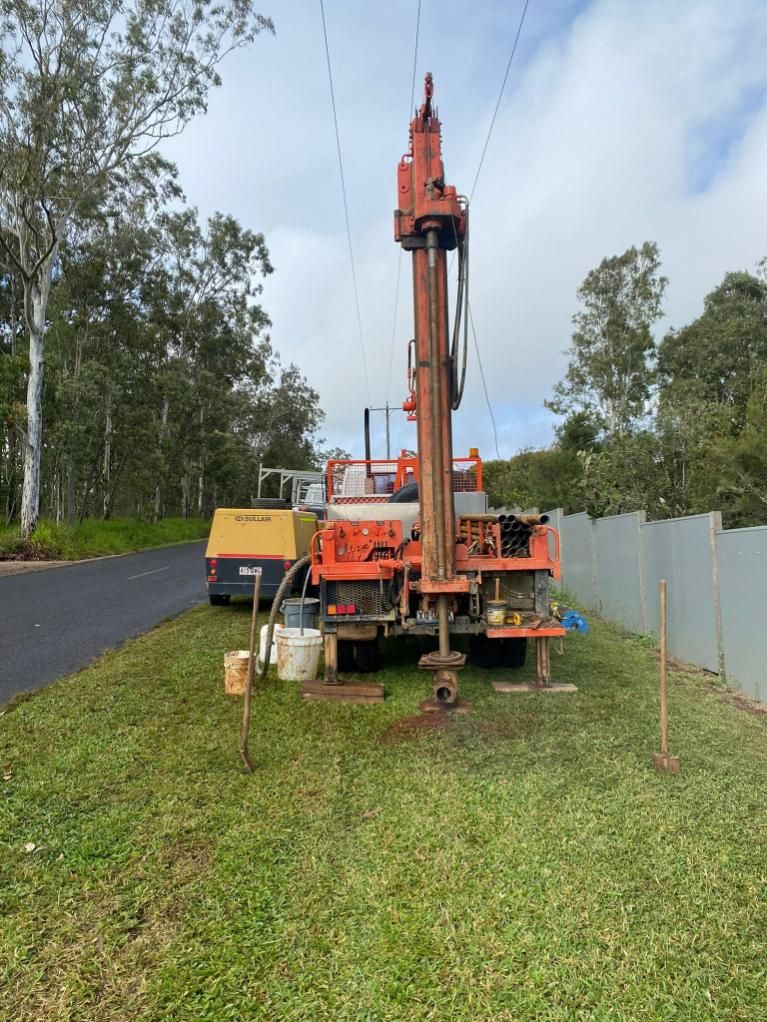 Large Orange Truck Is Parked In The Grass Next To A Road — FNQ Drilling in Cairns, QLD