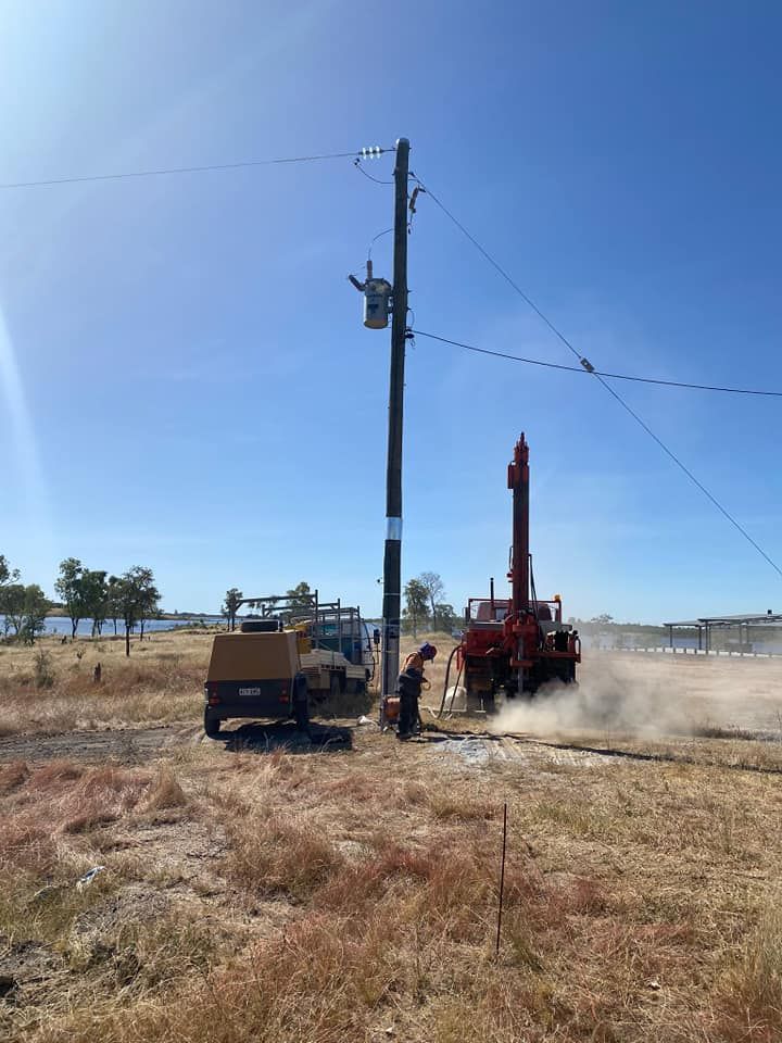 A Red Truck Is Drilling Down A Dirt Road Next To A Power Pole — FNQ Drilling in Bamboo, QLD