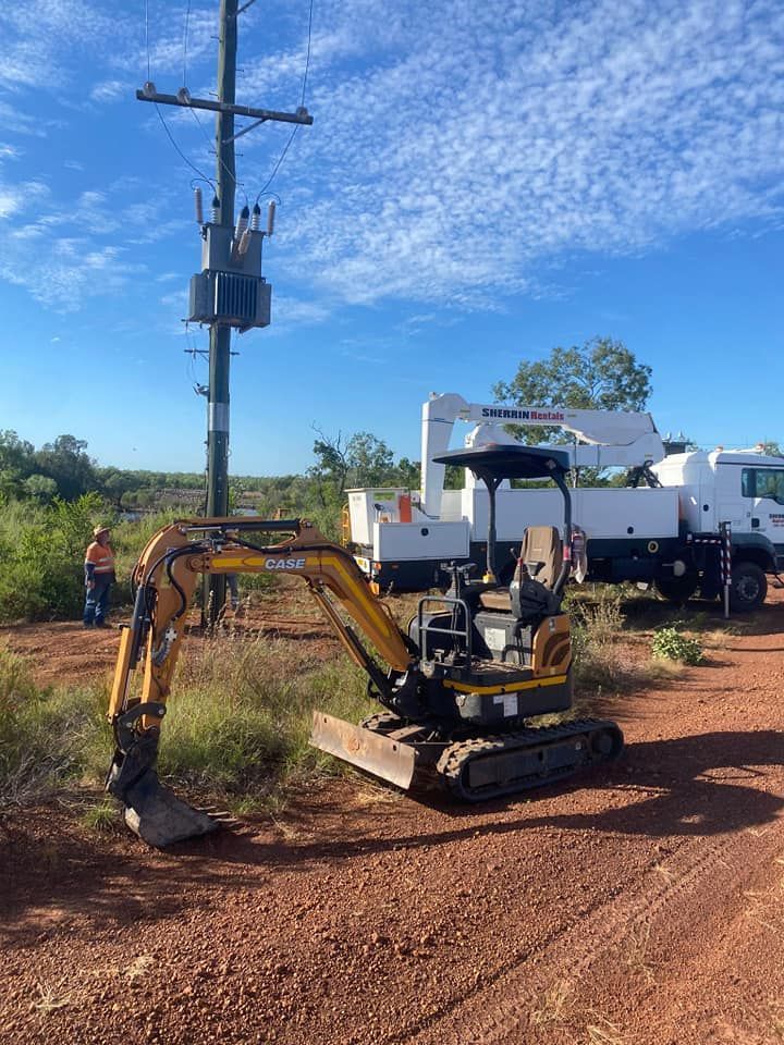 Small Yellow Excavator Is Parked Next To A Power Pole — FNQ Drilling in Georgetown, QLD