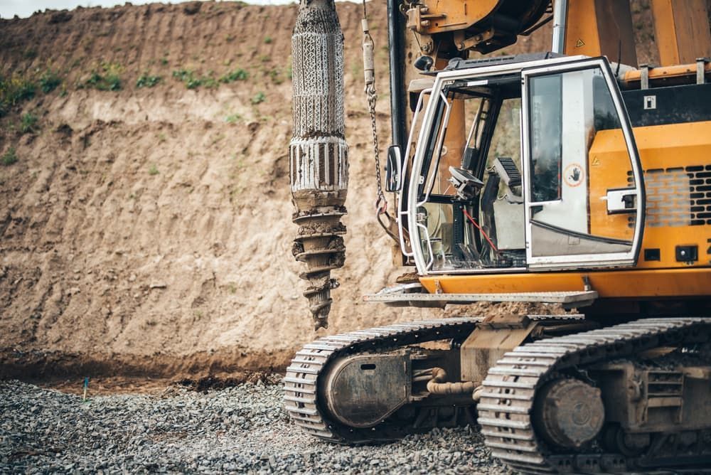 A Yellow Excavator is Working on a Construction Site — FNQ Drilling in Babinda, QLD