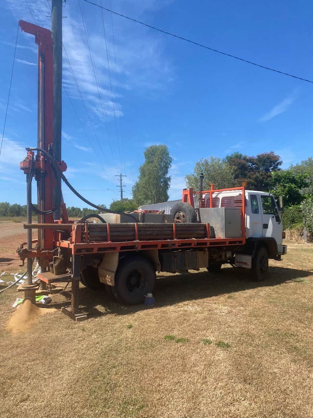 A Truck With a Drilling Rig on the Back is Parked in a Field — FNQ Drilling in Tully, QLD