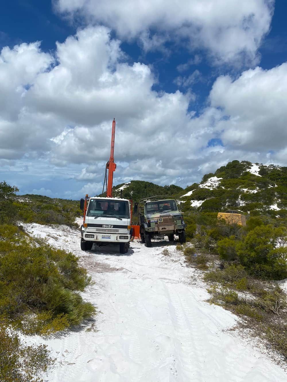 Two Trucks Are Parked on the Side of a Dirt Road — FNQ Drilling in Innisfail, QLD