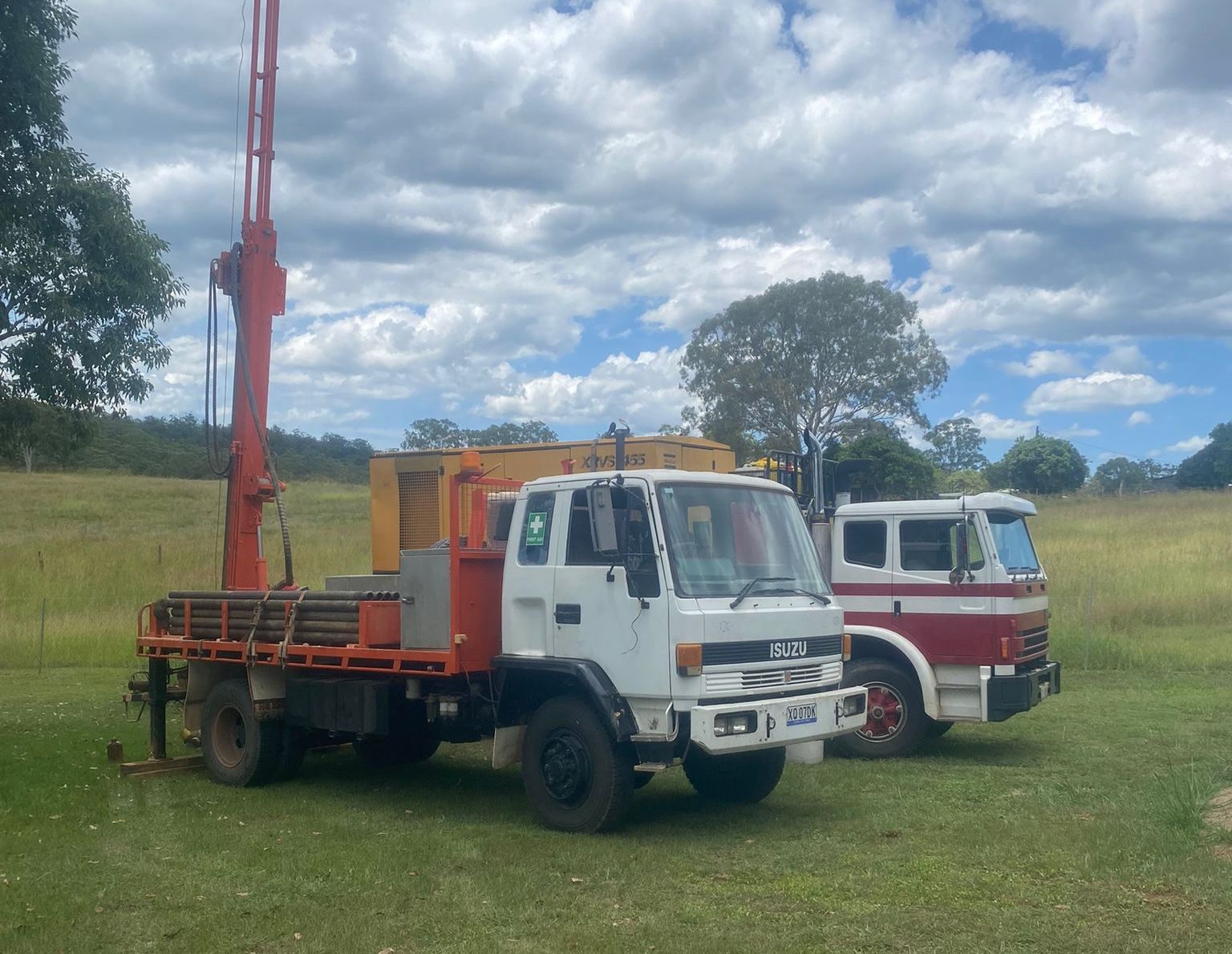 Two Men Is Standing Next To A Trailer With A Machine On It — FNQ Drilling in Bamboo, QLD