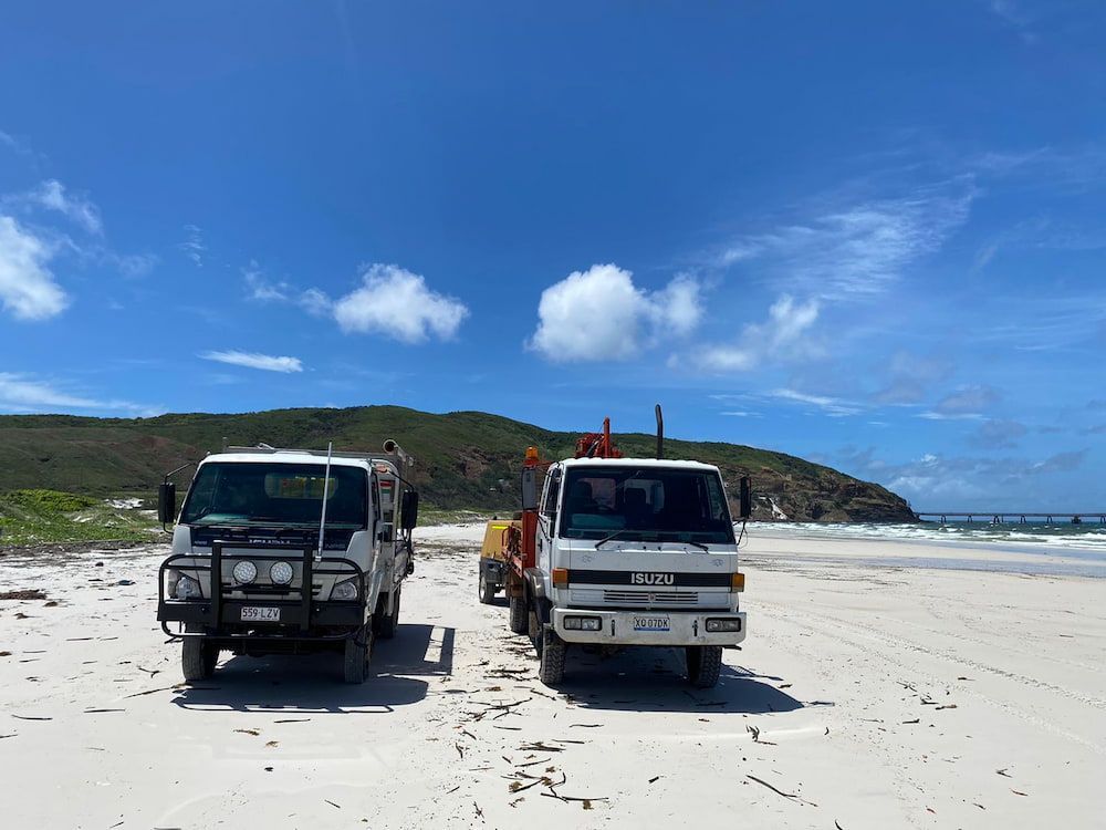 Two Trucks Are Parked on the Beach Next to Each Other — FNQ Drilling in Mareeba, QLD