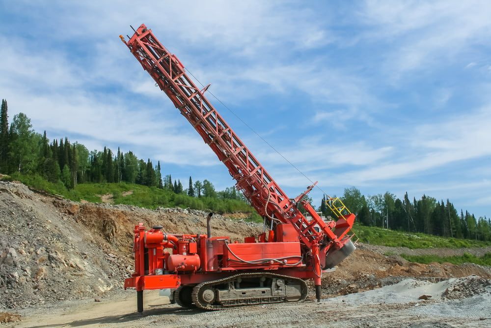 A Large Red Machine is Sitting on Top of a Dirt Hill — FNQ Drilling in Mareeba, QLD