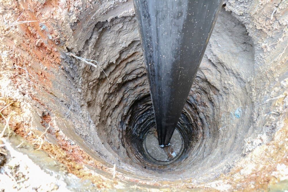 A Close Up of a Hole in the Ground With a Black Object in It — FNQ Drilling in Innisfail, QLD