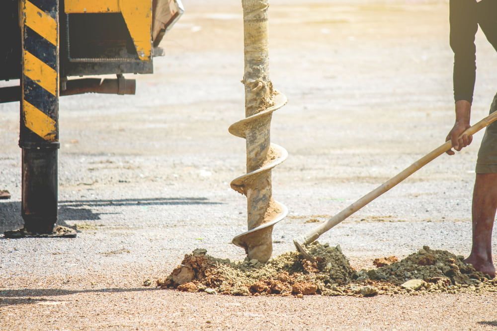 A Man is Using a Drill to Dig a Hole in the Ground — FNQ Drilling in Atherton, QLD