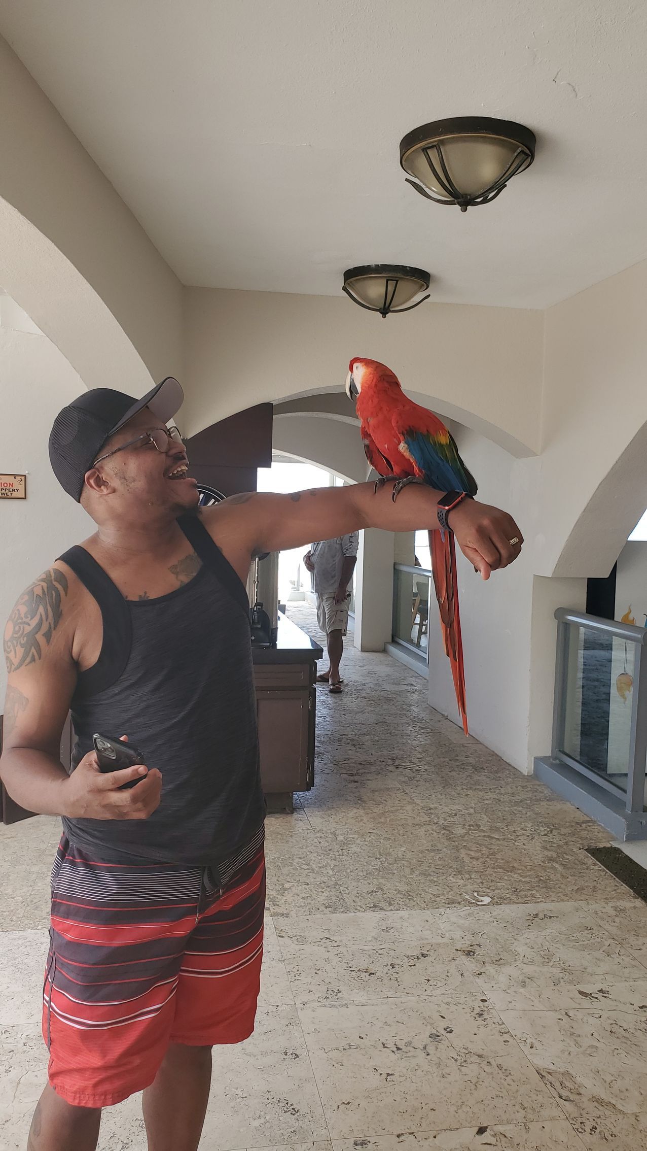 A man is holding a parrot on his arm.