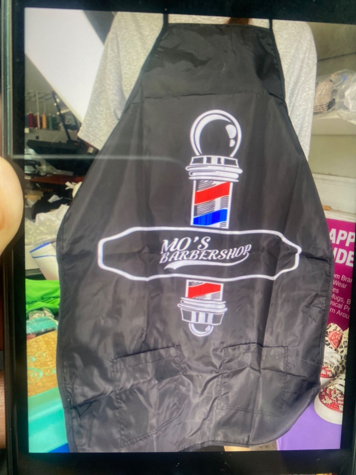 A black apron that says mo 's barber shop on it