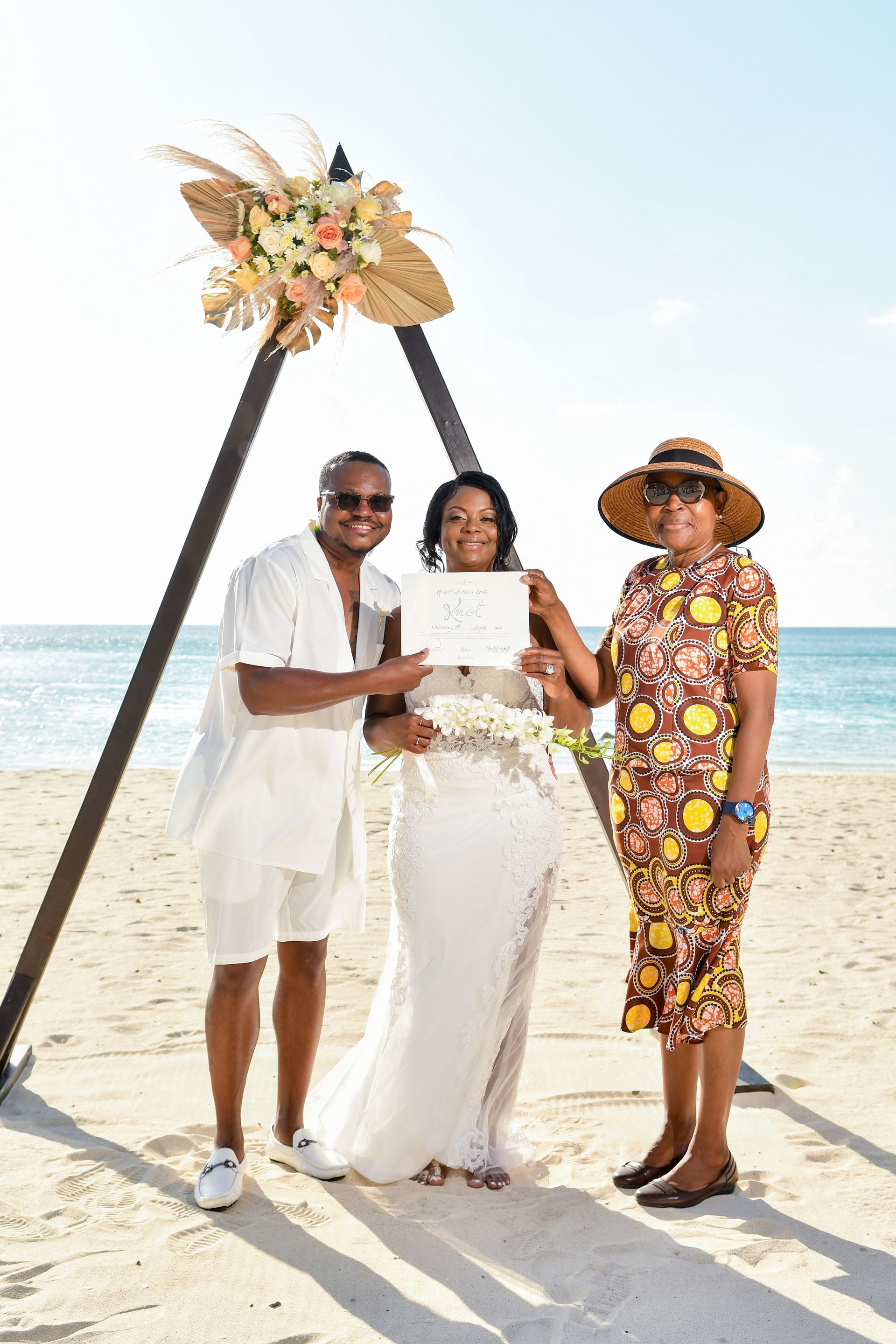 A bride and groom are posing for a picture on the beach.