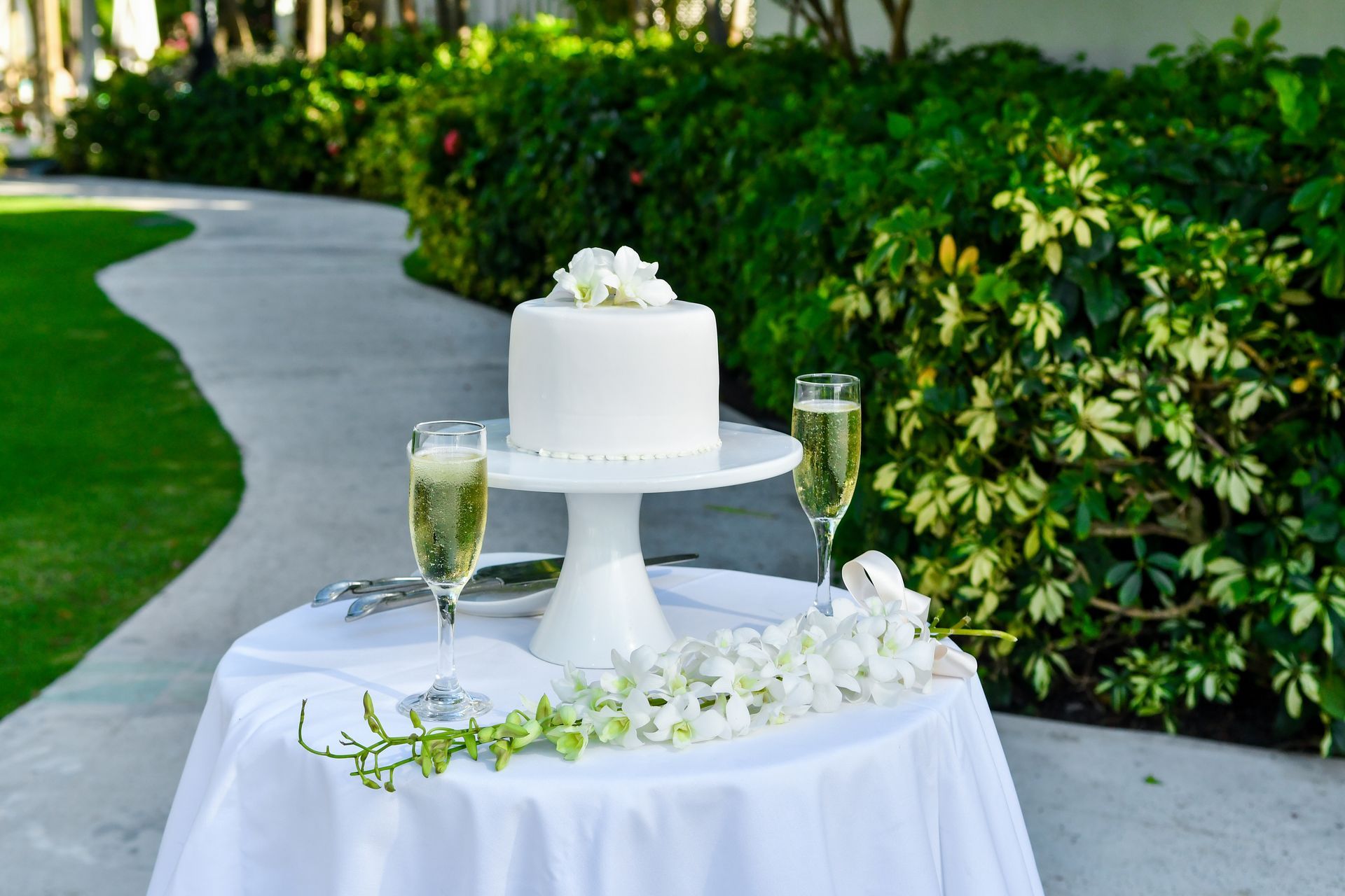A wedding cake and champagne glasses are on a table.