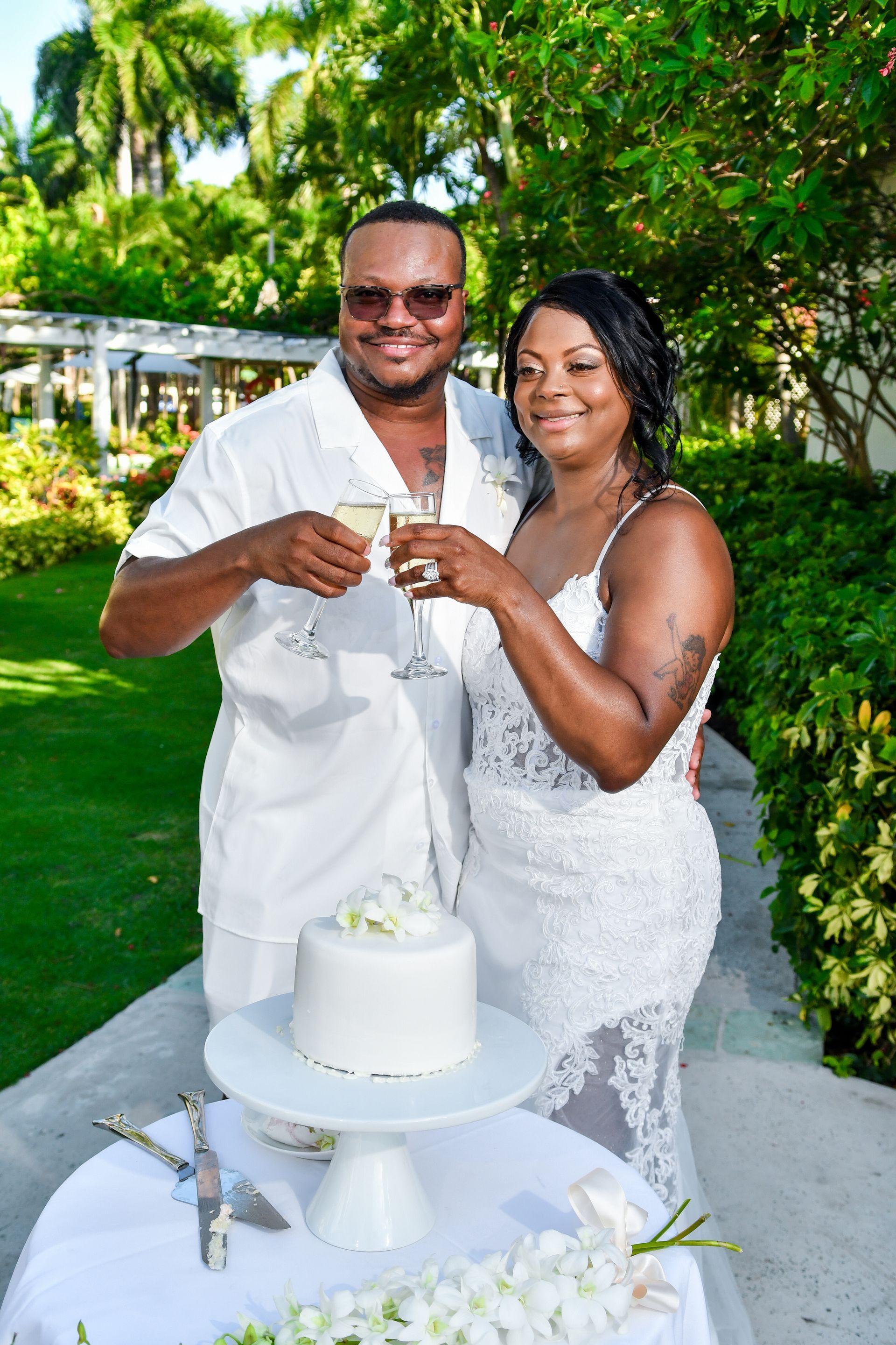 A man and a woman are toasting with champagne in front of a wedding cake.