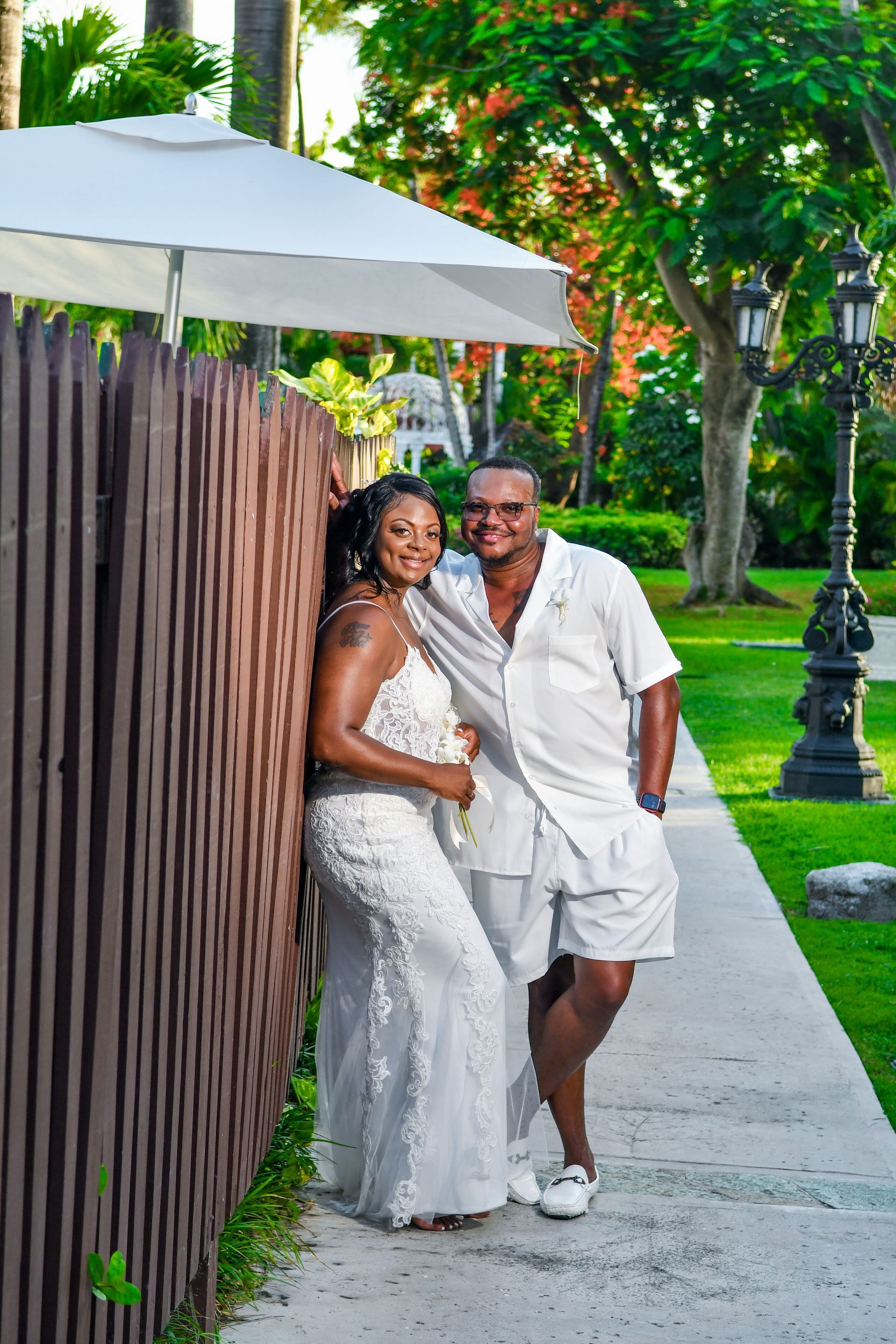 A man and a woman are posing for a picture next to a wooden fence.