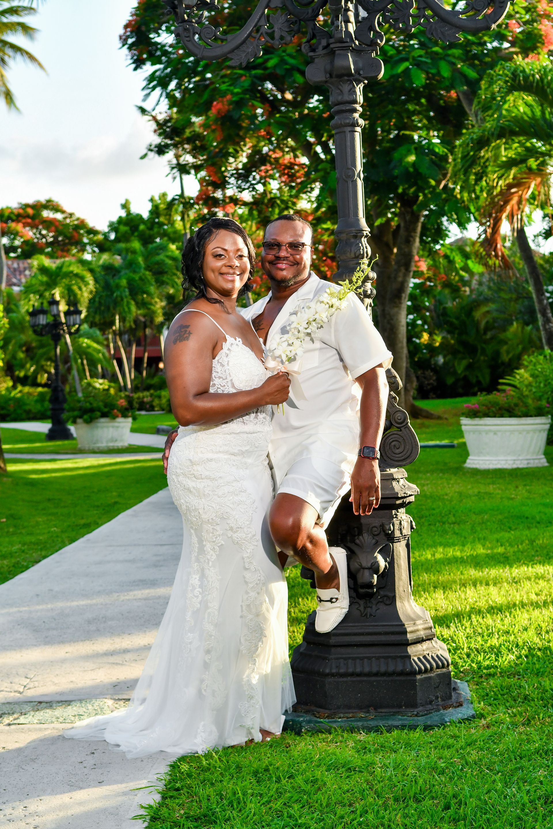 A bride and groom are posing for a picture in front of a street light.