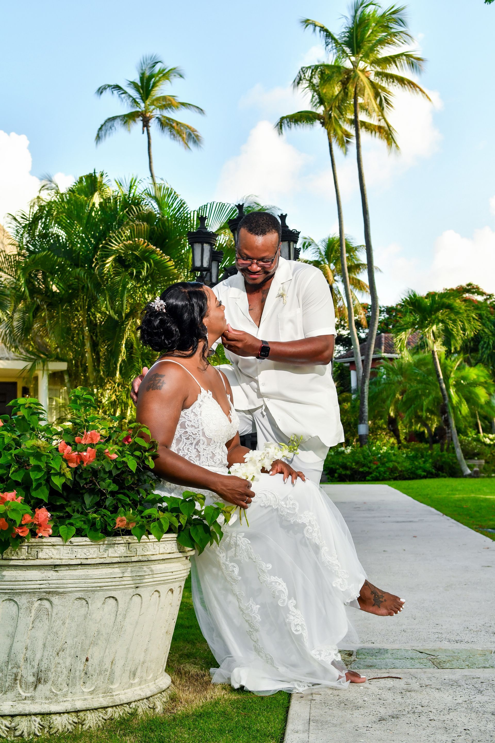A bride and groom are posing for a picture in front of palm trees.