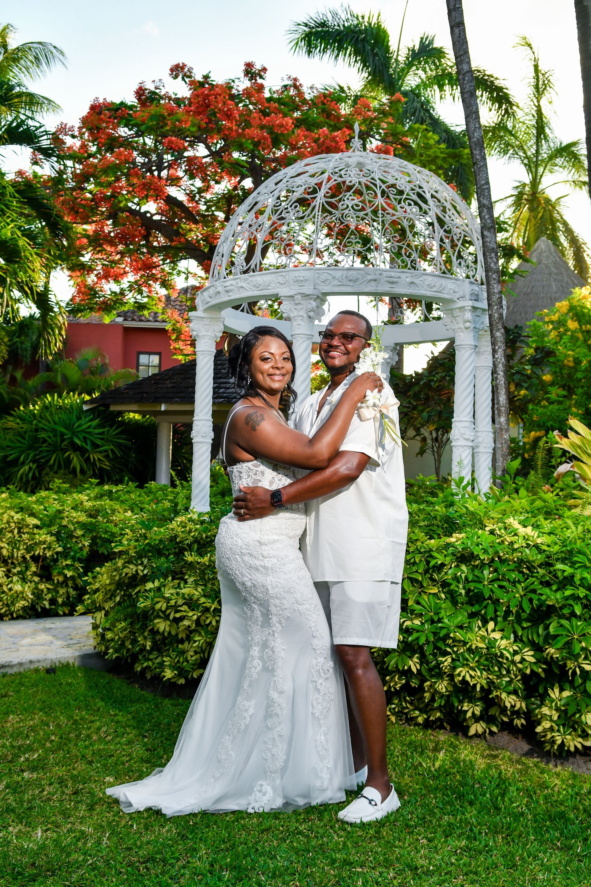 A bride and groom are posing for a picture in front of a gazebo.