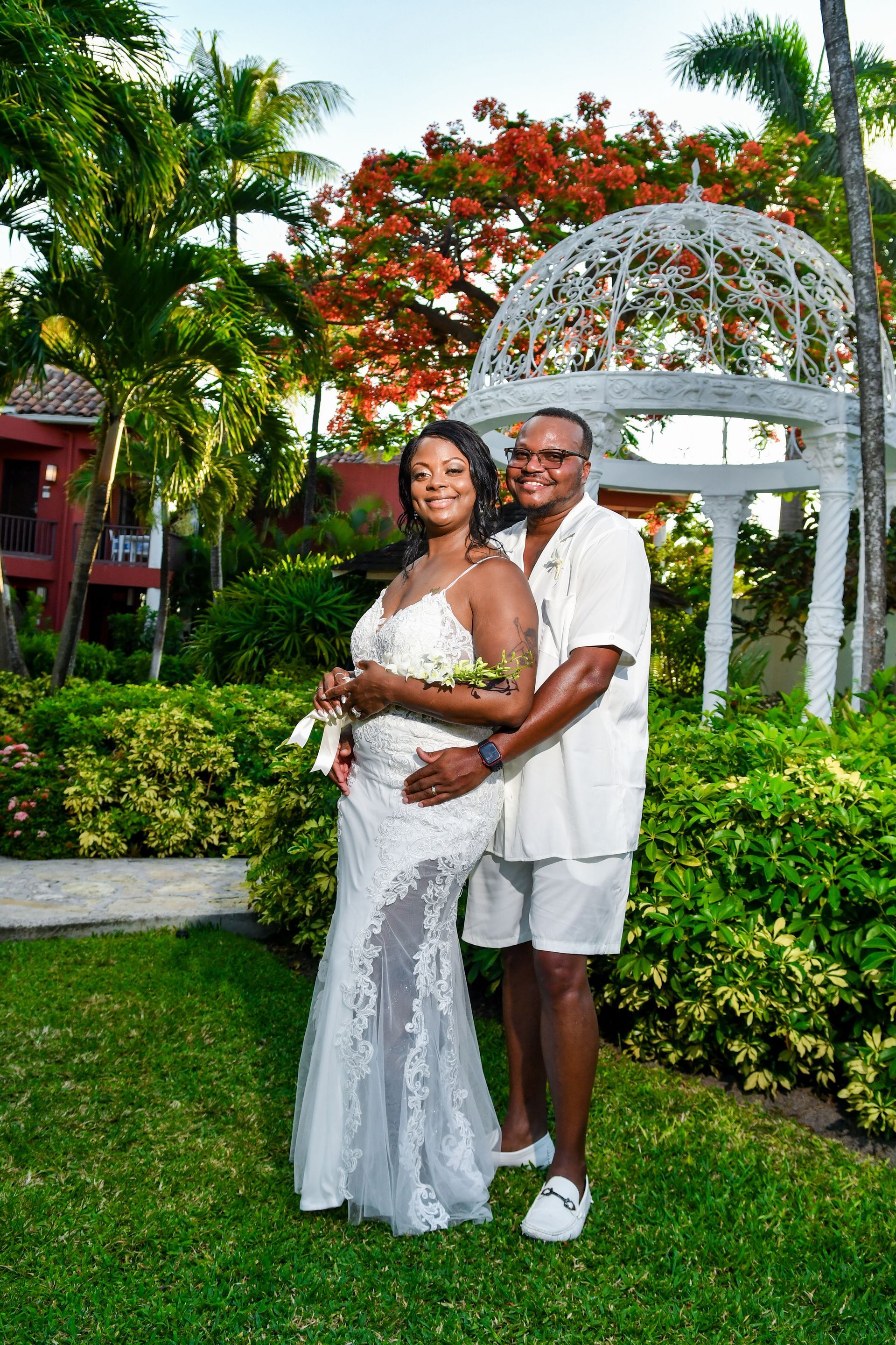 A bride and groom are posing for a picture in front of a gazebo.