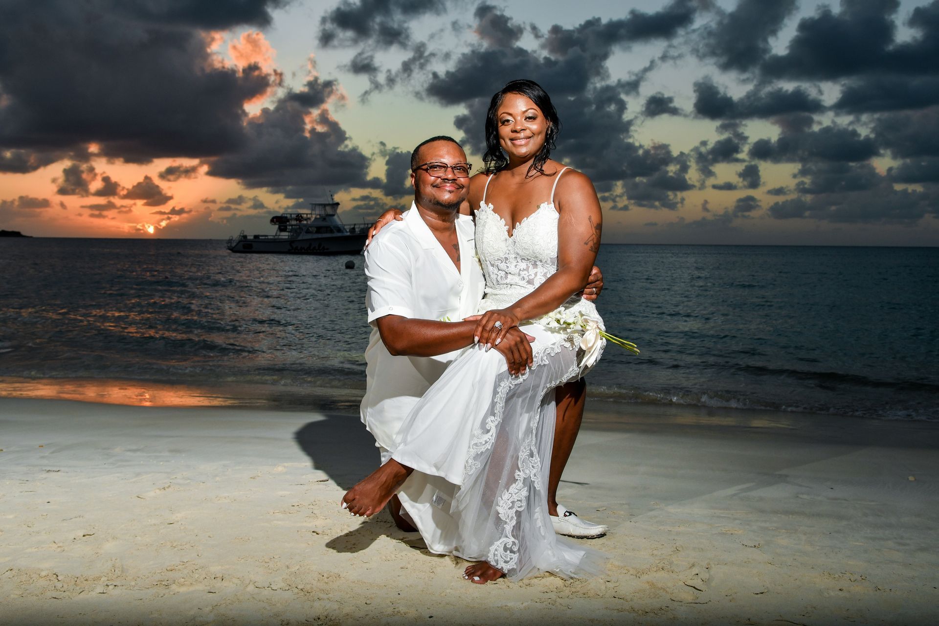 A bride and groom are posing for a picture on the beach.