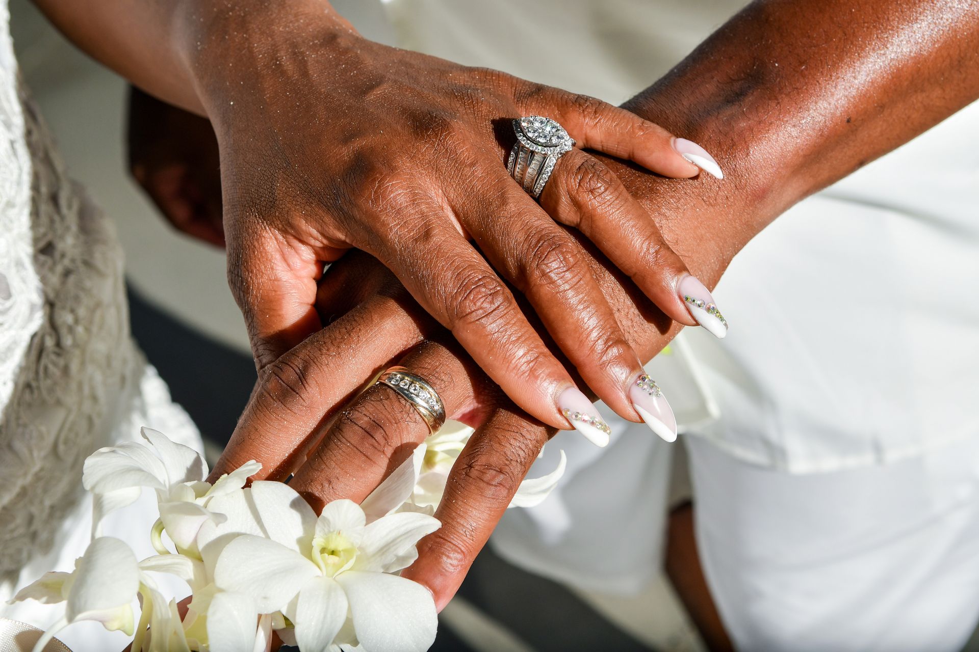 A bride and groom are holding hands with their wedding rings on their fingers.