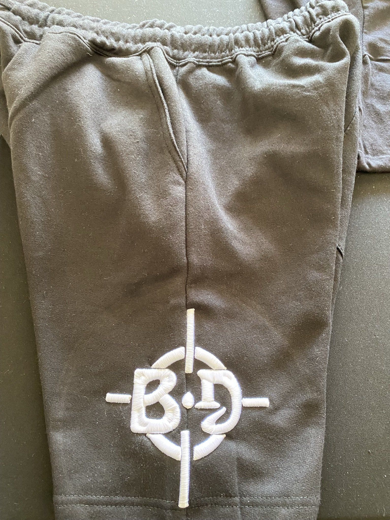 A pair of grey sweatpants with a white target on the side.