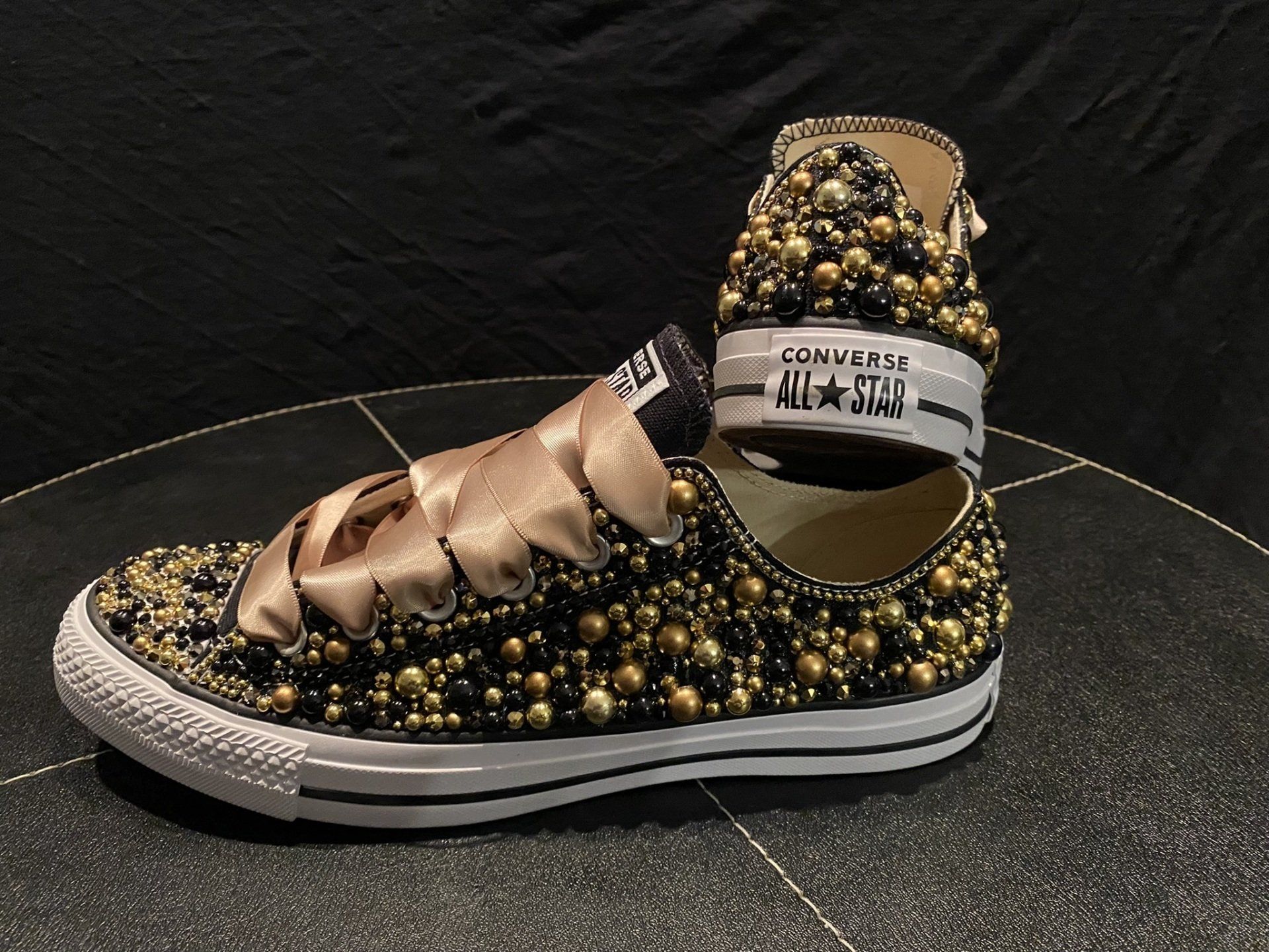 A pair of converse shoes with gold beads on them