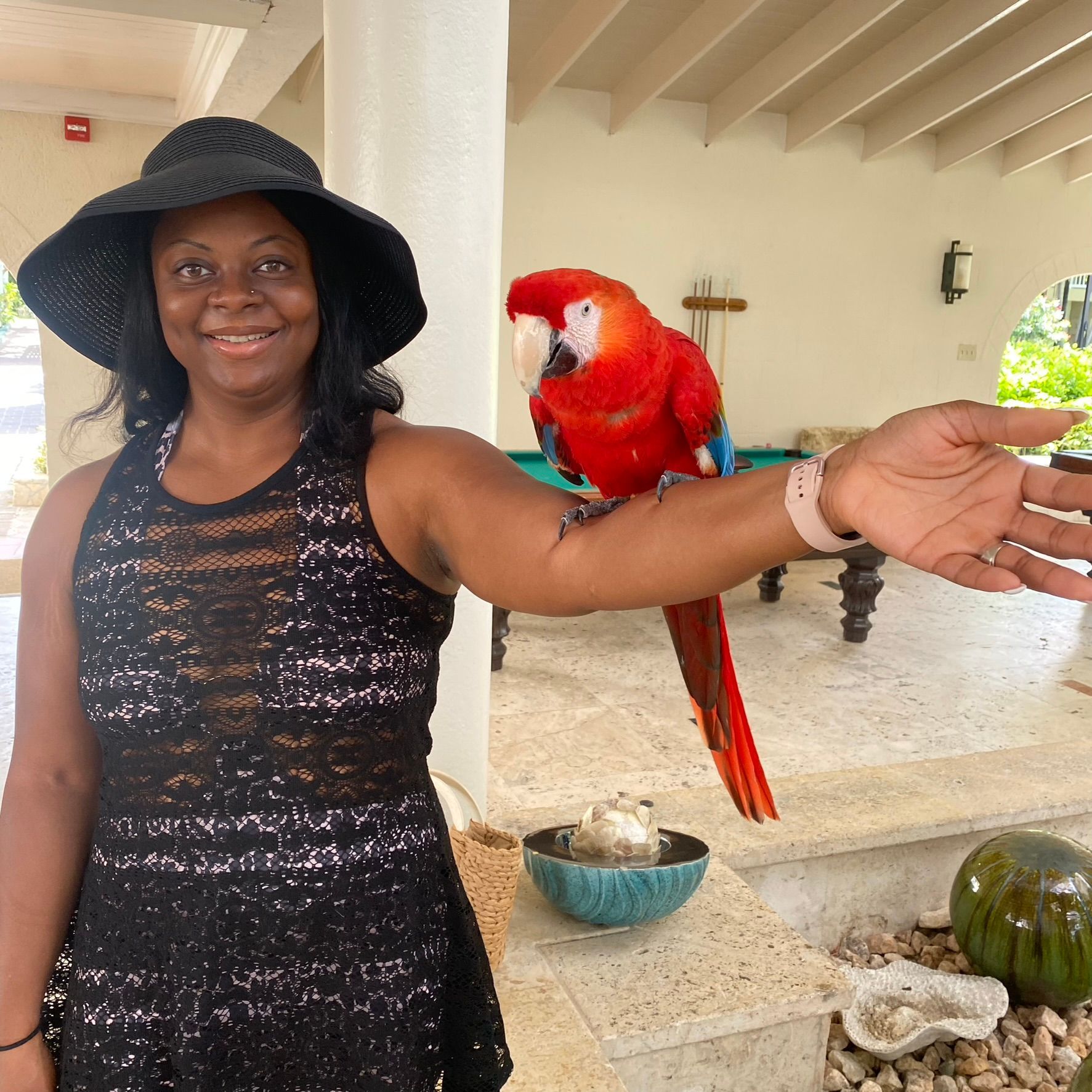 A woman with a red parrot on her arm
