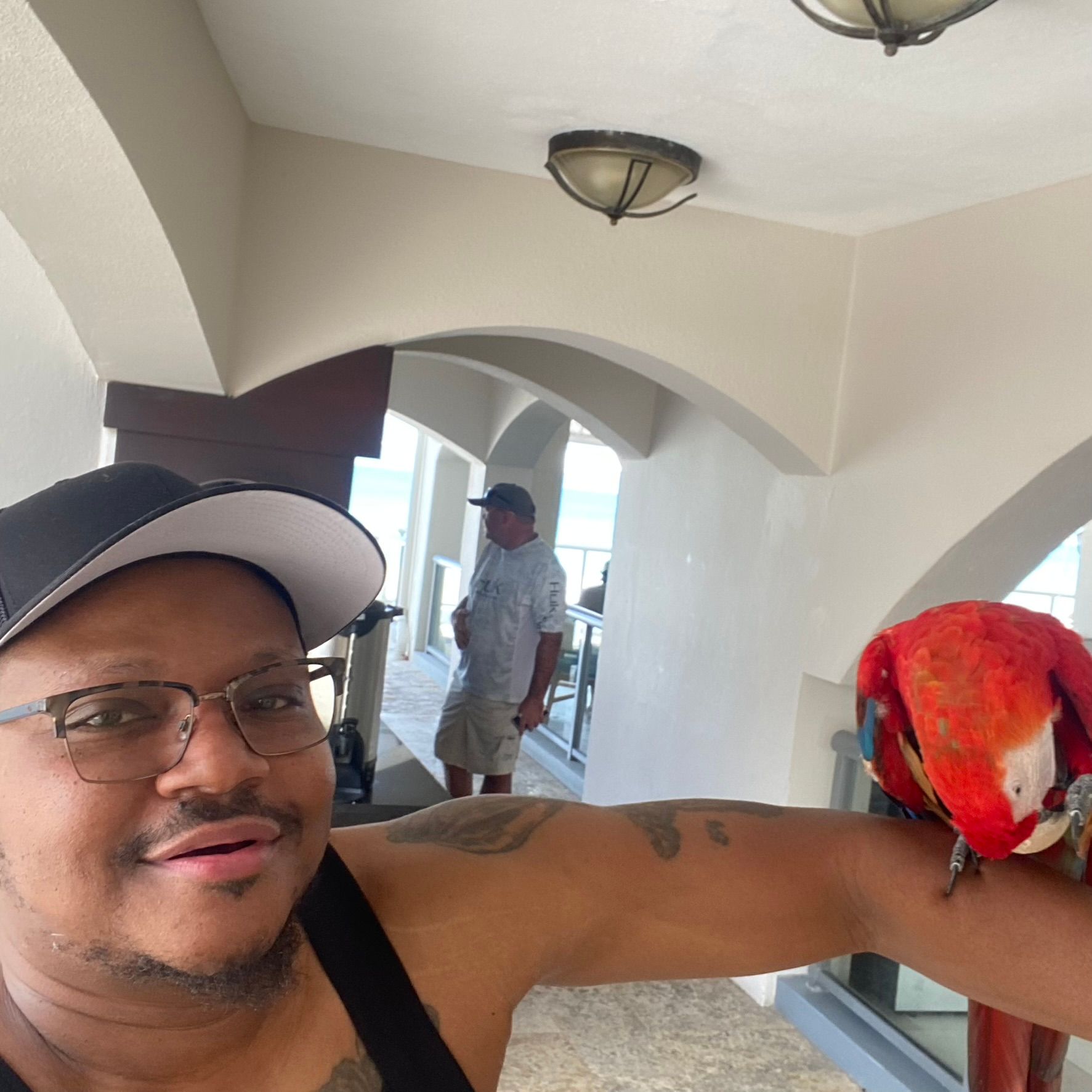 A man is holding a red parrot on his arm