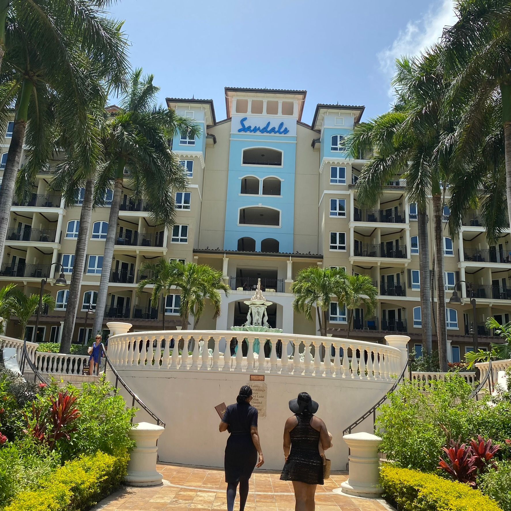 Two women are walking in front of a sandals hotel