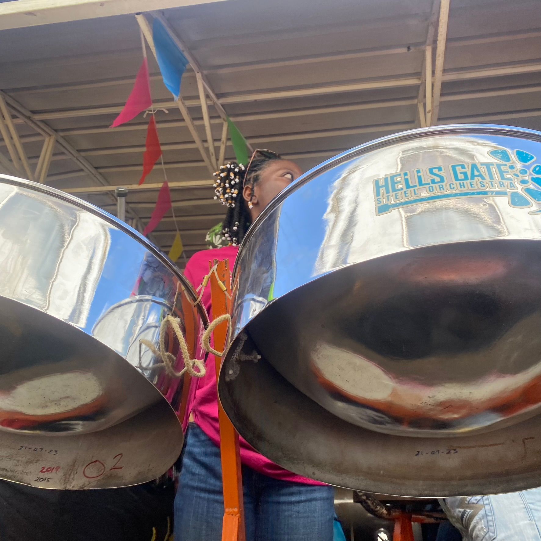 A woman in a pink shirt is playing steel drums